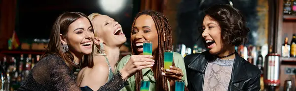Cheerful and stylish multiracial girlfriends with shot glasses laughing in modern bar, banner — Stock Photo