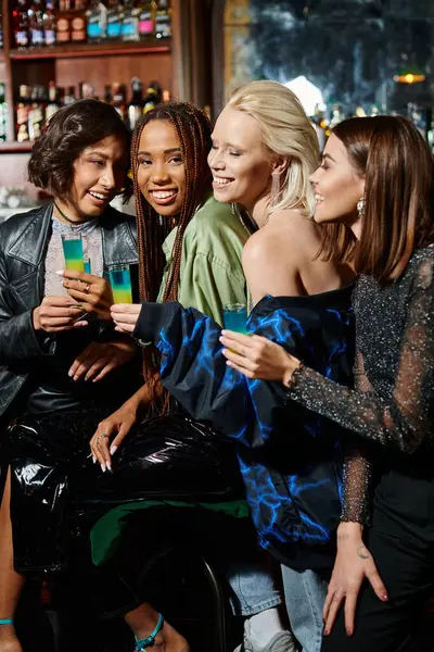 Glamour ed elegante multiculturale fidanzate tenendo bicchierini durante la festa nel bar moderno — Foto stock