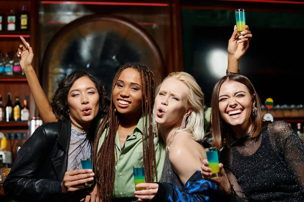 Excited multiethnic girlfriends pouting lips and looking at camera in bar, glamorous lifestyle — Stock Photo