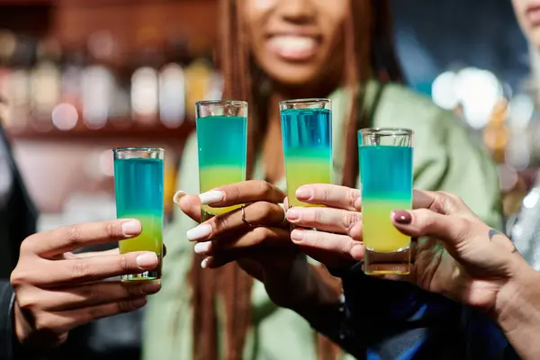 Cropped view of happy multiethnic female friends clinking shot glasses in bar, party time — Stock Photo