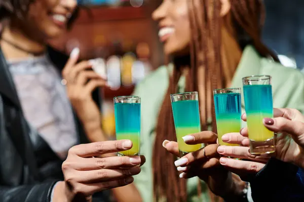 Vue recadrée des copines multiraciales floues tenant des verres de tir dans le bar moderne, fête de poule — Photo de stock