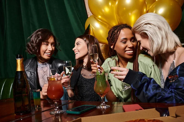 Gioiose donne multirazziali che festeggiano il compleanno con champagne, cocktail e palloncini d'oro nel bar — Foto stock