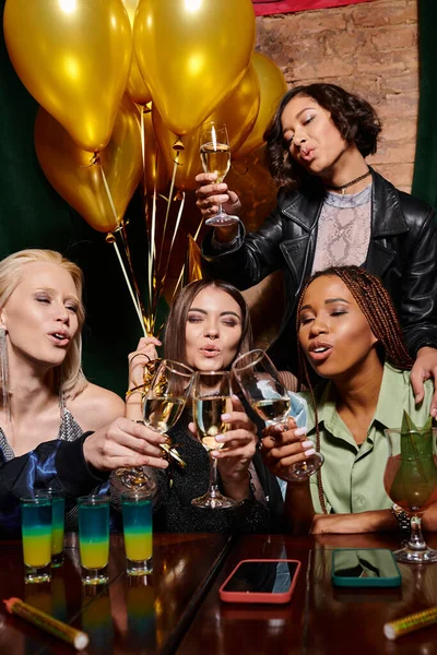 Diverso grupo de novias multiétnicas tintineo copas de champán durante la fiesta de cumpleaños en el bar - foto de stock