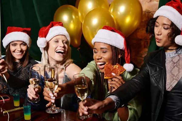 Excitado multicultural novias tintineo copas de champán mientras se celebra la Navidad en el bar - foto de stock