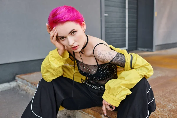 Fashionable appealing woman in stylish outfit with pink hair and tattoos looking at camera, fashion — Stock Photo