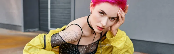 Seductora mujer elegante con el pelo rosa y tatuajes posando en la calle y mirando a la cámara, pancarta - foto de stock