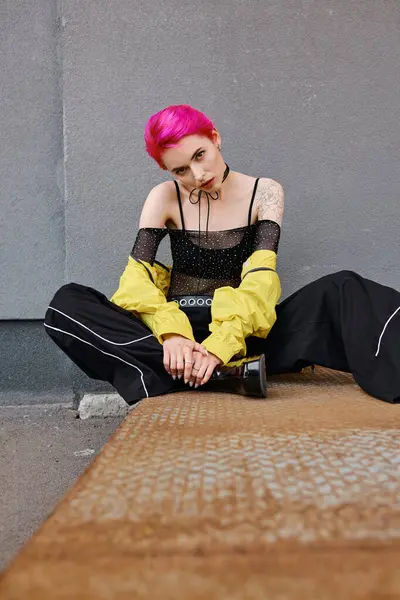 Giovane donna attraente con i capelli corti rosa e tatuaggi seduti e guardando la macchina fotografica, moda — Foto stock