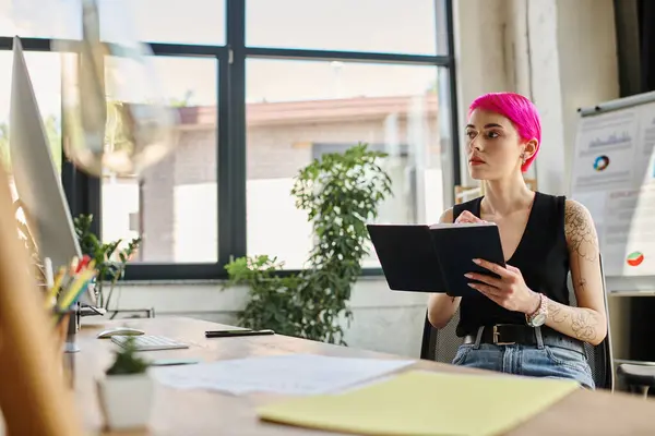 Thoughtful pink haired woman with tattoos sitting with notes and pen in hands, business concept — Stock Photo