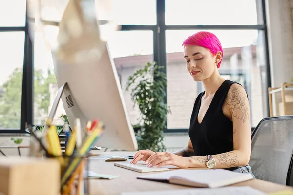 Cheerful young businesswoman in casual urban outfit smiling while working hard at computer — Stock Photo