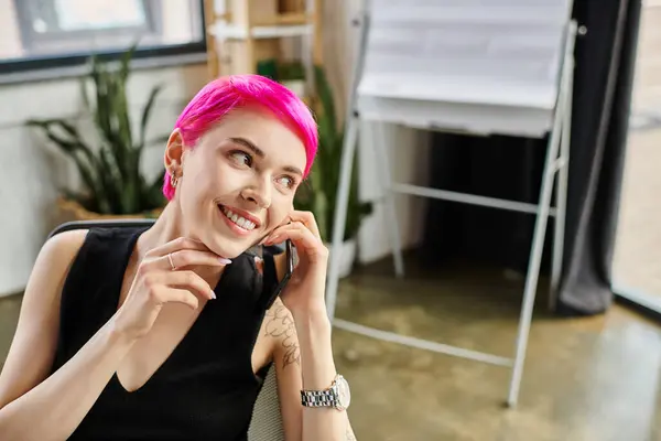 Joyous pink haired woman with tattoos talking by phone while working hard, business concept — Stock Photo