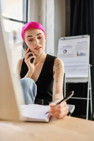 Pink haired young female worker in casual outfit taking notes and talking by phone, business concept — Stock Photo
