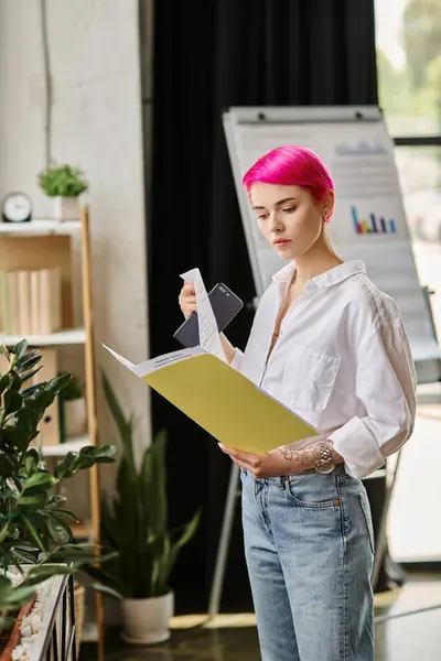 Pink haired beautiful businesswoman in white shirt and jeans looking at her notes and holding phone — Stock Photo