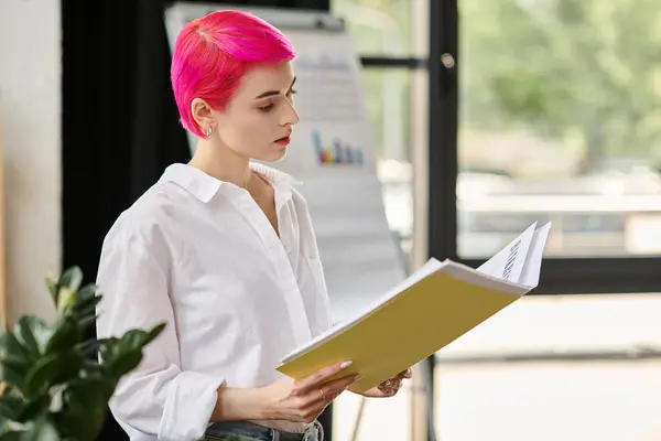 Réfléchie jeune femme d'affaires avec les cheveux courts roses en tenue décontractée en regardant ses notes au bureau — Photo de stock