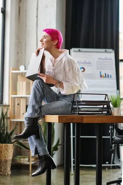 Jolly beautiful woman in white shirt and jeans sitting with laptop on knees, business concept — Stock Photo