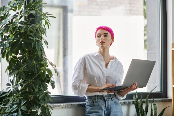 Красивая молодая работница в белой рубашке и джинсах держа ноутбук и глядя в сторону, бизнес — стоковое фото