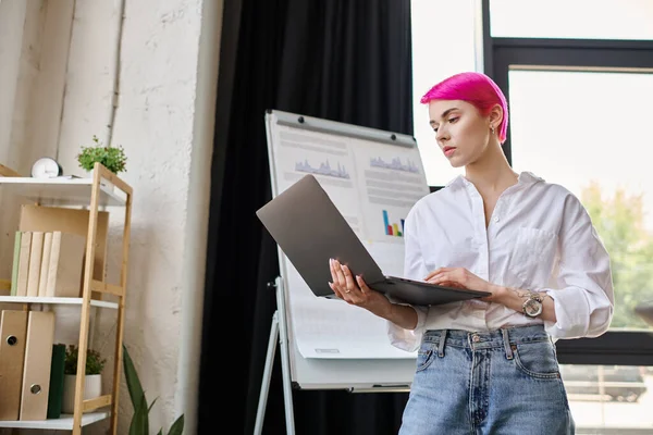 Attractive woman with tattoos in white shirt looking at her laptop at office, business concept — Stock Photo