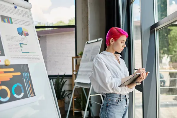 Giovane donna d'affari attraente con i capelli rosa in camicia bianca prendere i suoi appunti mentre in ufficio — Foto stock