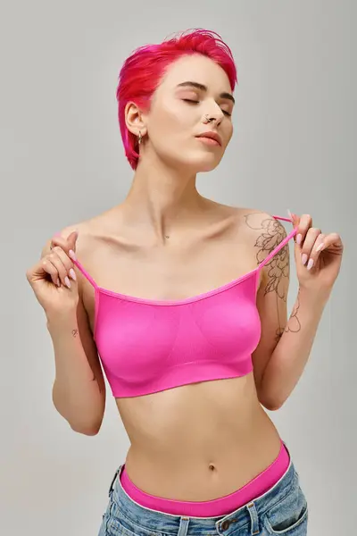 Молода жінка в рожевій верхній частині культури і джинси з татуюваннями, позує із закритими очима, концепція моди — стокове фото
