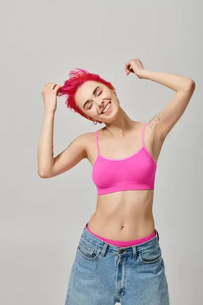 Happy pink haired woman with tattoos posing with closed eyes on grey backdrop, fashion concept — Stock Photo