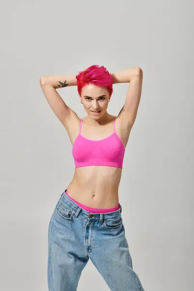 Seductora modelo femenina con el pelo rosa y tatuajes posando y mirando a la cámara, concepto de moda - foto de stock