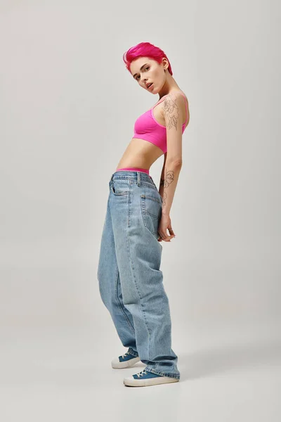 Verführerisch tätowierte weibliche Modell in trendiger Kleidung beugt Körper leicht und blickt in die Kamera — Stockfoto