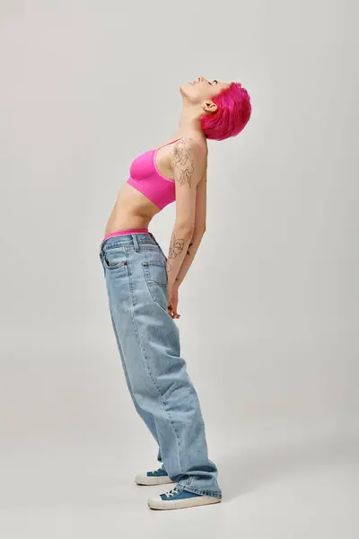 Молода приваблива жінка у верхній і синій джинсах злегка згинає її тіло, концепція моди — стокове фото