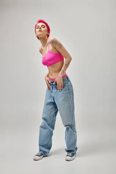 Appealing female model with tattoos and pink hair leaning slightly and looking at camera, fashion — Stock Photo