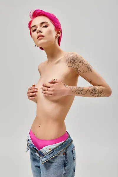 Татуированная и безликая молодая женщина с розовыми волосами, покрывающими грудь руками на сером заднике — стоковое фото