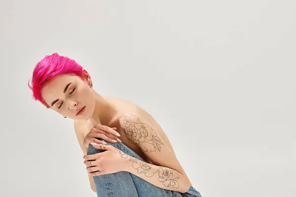 Sensual and topless woman with pink hair sitting in denim jeans on grey background, dreamy — Stock Photo