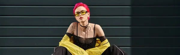 Jeune femme aux cheveux roses et tatouage posant en lunettes de soleil jaunes et tenue élégante, bannière — Photo de stock