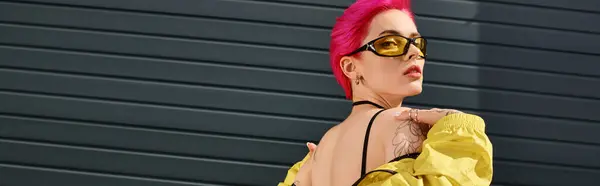 Pink haired young woman in yellow sunglasses and trendy outfit posing and looking at camera, banner — Stock Photo