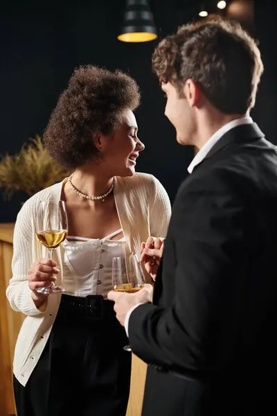 Happy african american woman holding wine glass and hand of man during date on valentines day — Stock Photo