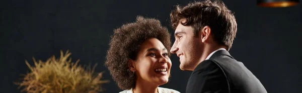 Happy african american woman smiling and looking at man during date on valentines day, banner — Stock Photo