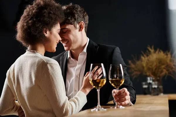 Happy interracial couple spending great time near glasses of wine during date on Valentines Day — Stock Photo