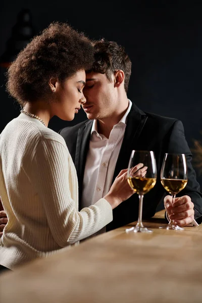 Young interracial couple spending great time near glasses of wine during date on Valentines Day — Stock Photo