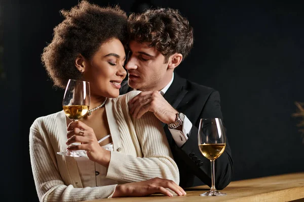 Bonito homem flertando com Africano americano mulher sentado no bar contador com copo de vinho durante data — Fotografia de Stock
