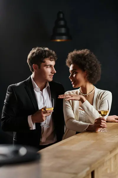 Beautiful interracial couple holding glasses of white wine while having date on Valentines day — Stock Photo