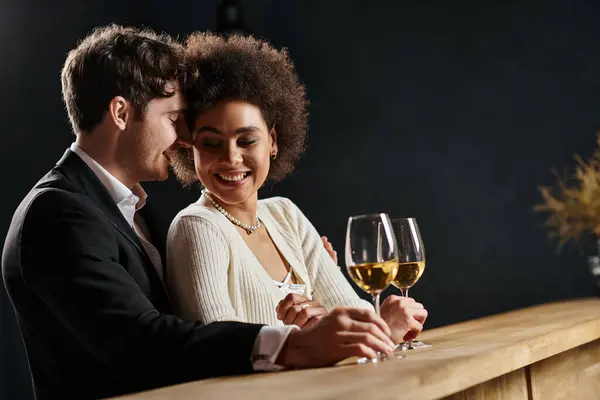 Happy interracial couple sitting at bar counter with wine glasses and having date on Valentines day — Stock Photo