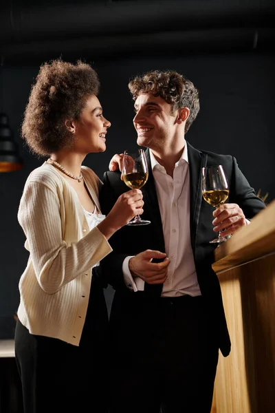 Happy couple looking at each other while holding glasses of white wine during date on 14 February — Stock Photo