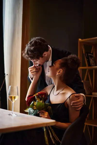Джентльмен целует руку африканской американки держащей розы во время свидания на День Святого Валентина — стоковое фото
