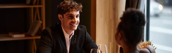 Happy man in elegant attire looking at girlfriend with glass of wine during date, horizontal banner — Stock Photo