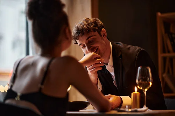 Happy gentleman in elegant attire kissing hand of girlfriend during date on Valentines day — Stock Photo