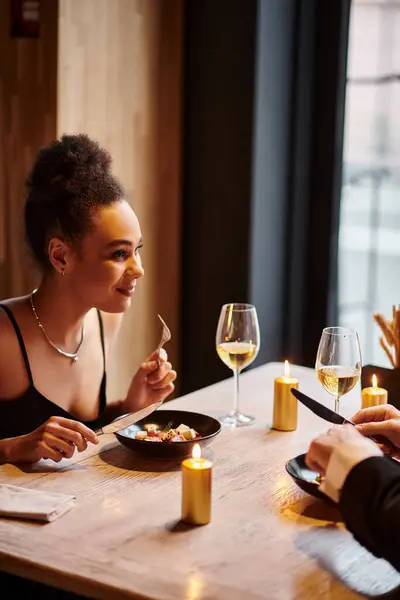 Щаслива афроамериканська жінка насолоджується вечерею поруч з хлопцем під час побачення в день Святого Валентина — стокове фото