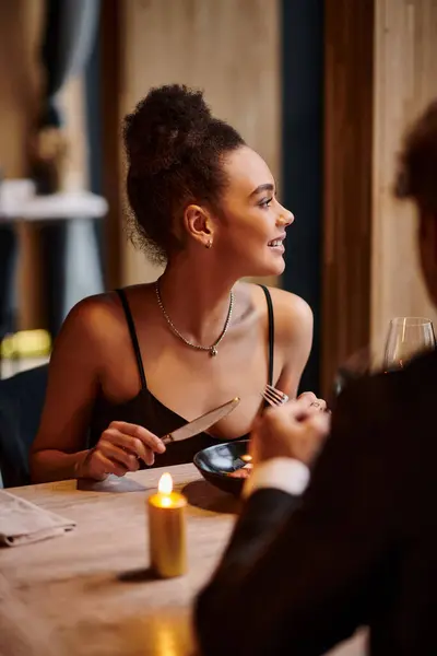 Feliz mulher afro-americana desfrutando de refeição ao lado do namorado durante a noite de encontro no dia dos namorados — Fotografia de Stock