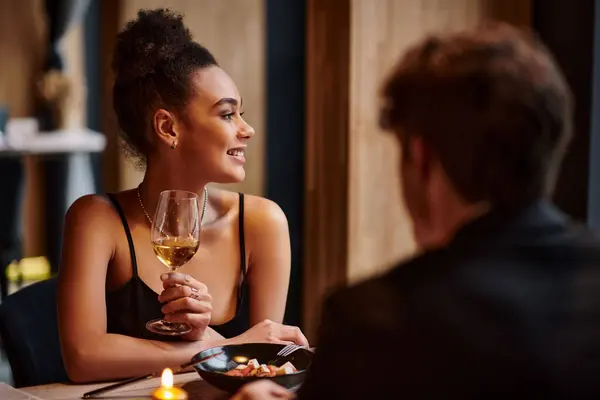 Heureuse femme afro-américaine tenant verre de vin à côté de petit ami pendant la date sur la Saint Valentin — Photo de stock