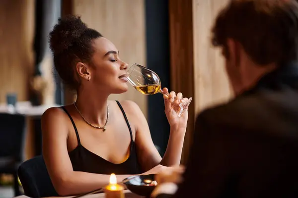 Feliz afro-americana bebendo vinho branco ao lado do namorado durante a data no dia dos namorados — Fotografia de Stock