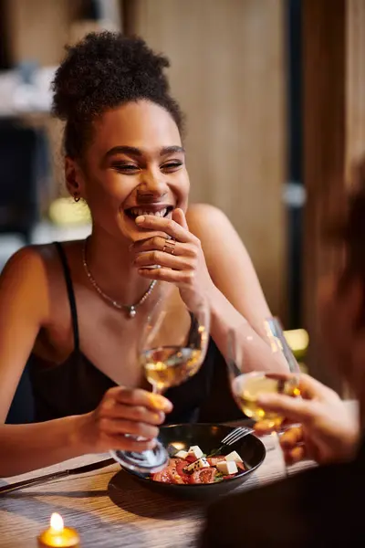 Mujer afroamericana feliz riendo sinceramente durante la fecha en el día de San Valentín, cena romántica - foto de stock