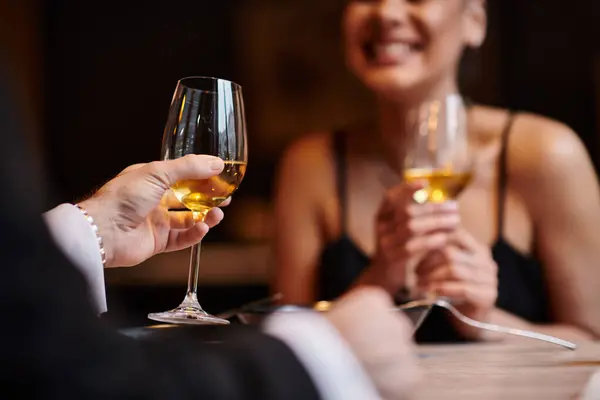 Cropped view of man holding glasses of wine near woman during romantic dinner on Valentines day — Stock Photo