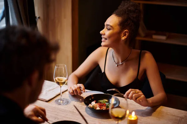 Heureuse femme afro-américaine manger de la salade pendant la date avec petit ami au restaurant, Saint Valentin — Photo de stock