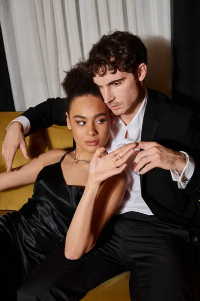 Молода афроамериканка в чорному одязі і красивий чоловік в елегантному костюмі сидить на оксамитовому дивані — стокове фото